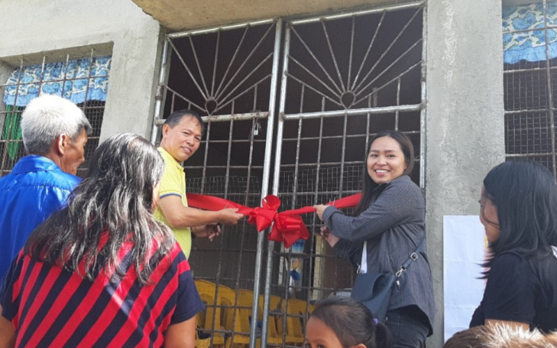 Man-and-woman-cutting-ribbon-in-front-of-their-new-church-building